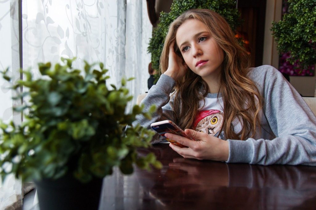 Keeping Kids Safe: image of sad teenaged girl with cell phone