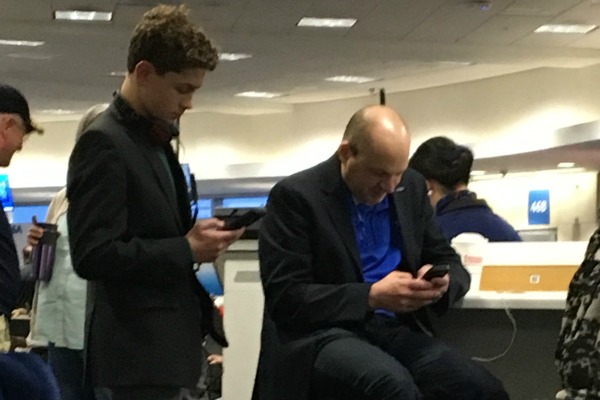 Time Management 102: Image of a father and son checking email in an airport.