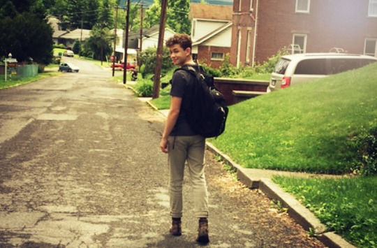 Image of a high school boy with a backpack on walking to his first day of school.